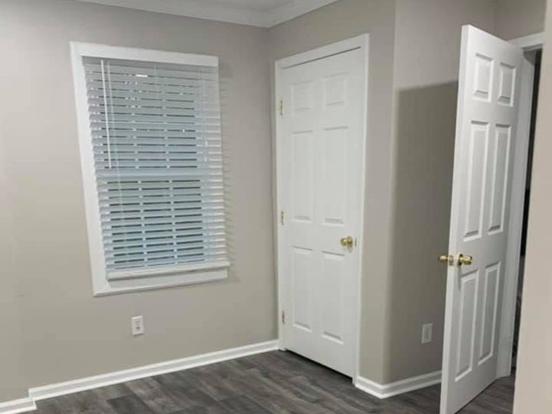 Bedroom with gray walls, white trim and doors, and gray plank flooring
