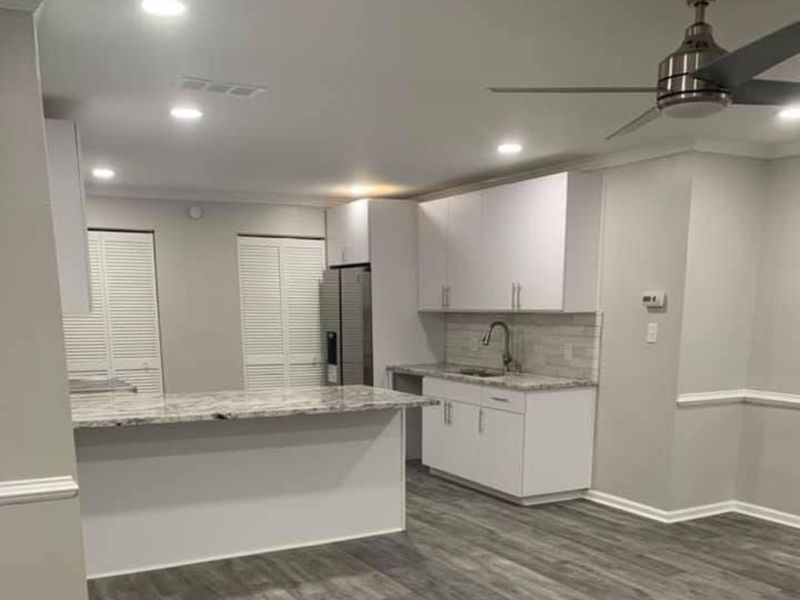 Finished kitchen with white cabinets, a stone-top island, and gray plank flooring
